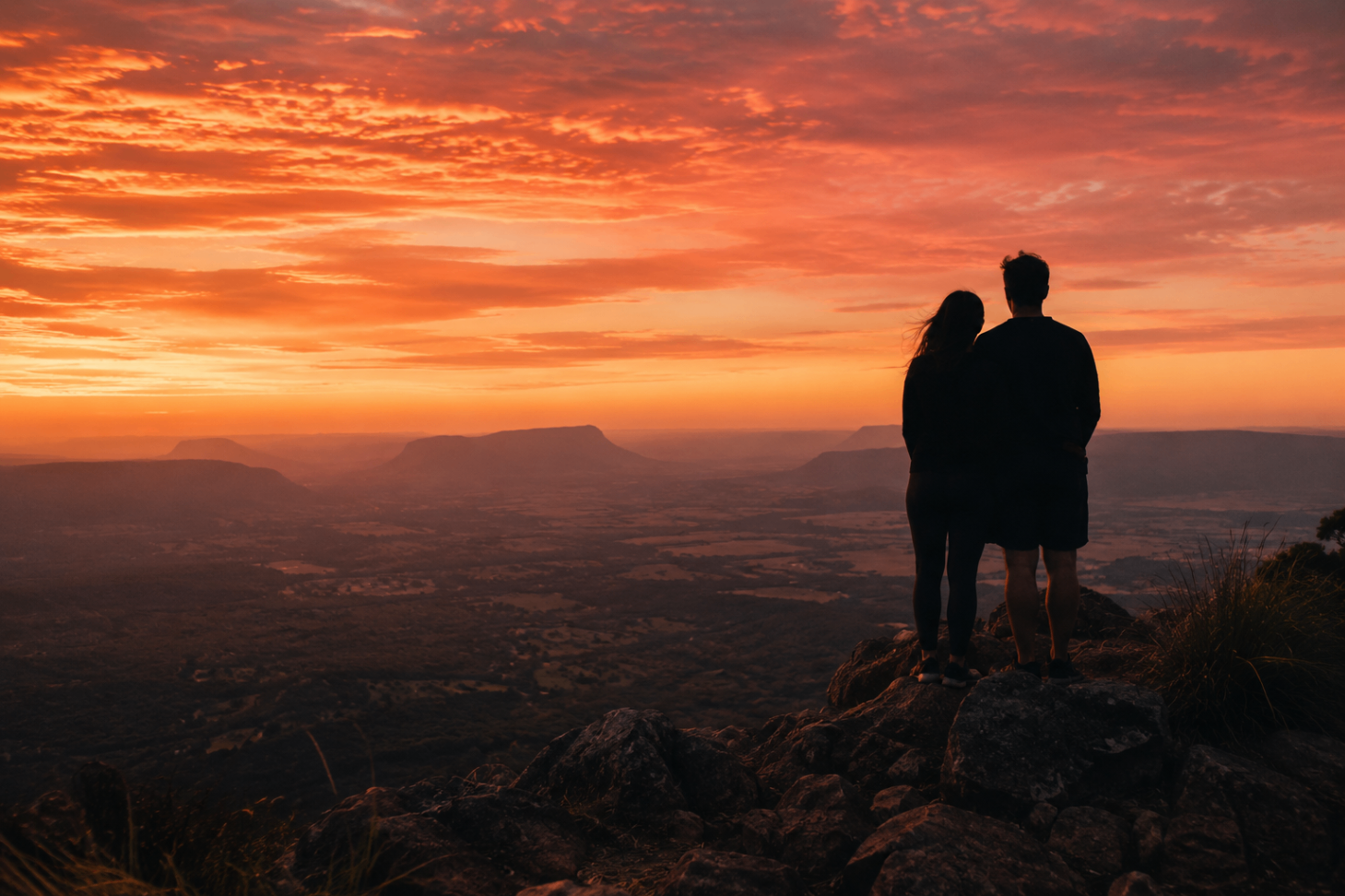 A couple silhouetted against a fiery orange sunset sky