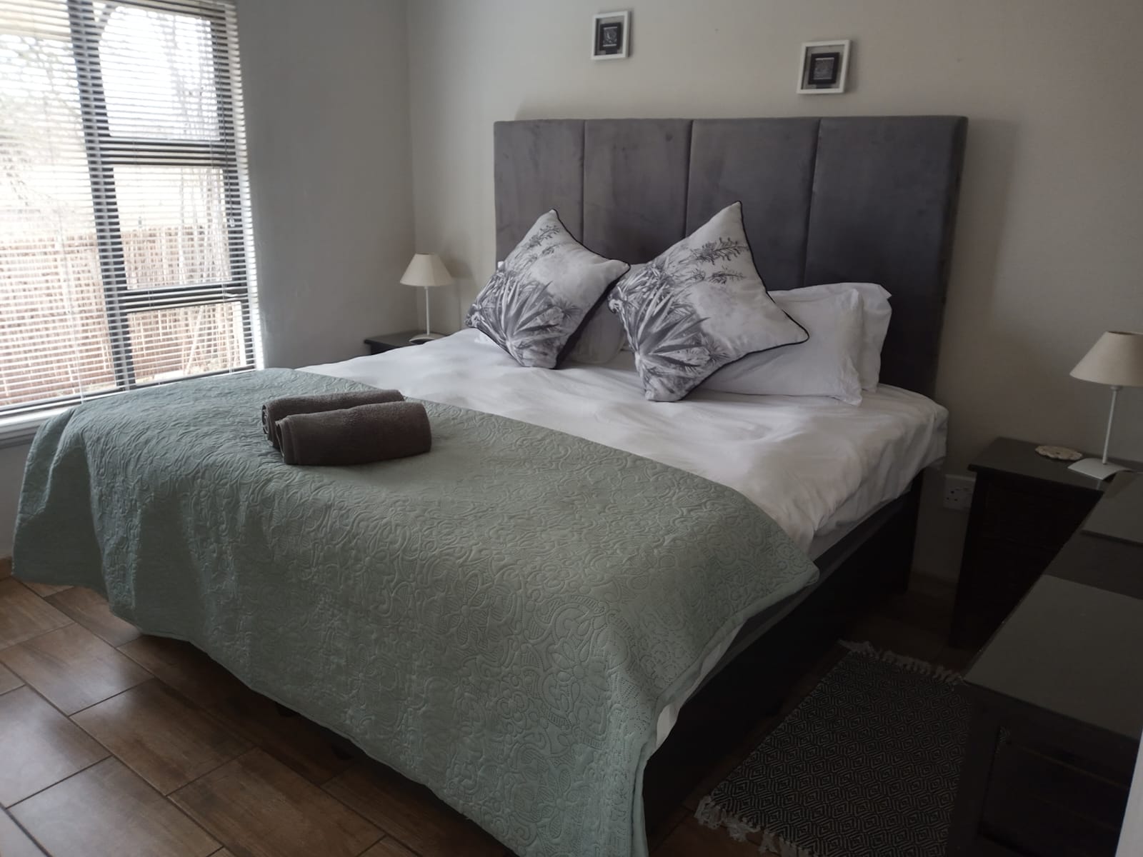 Main bedroom with pale green linen and bedside lamps in the Aloe Suite