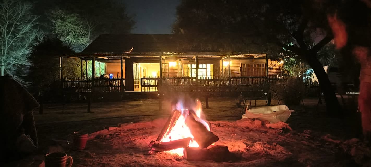 Communal boma with an evening fire and warm lodge lighting at Acacia Lodge
