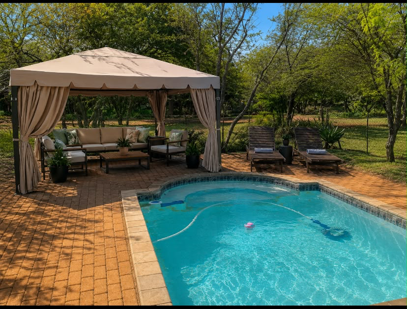 A private swimming pool with a shaded gazebo and loungers surrounded by trees