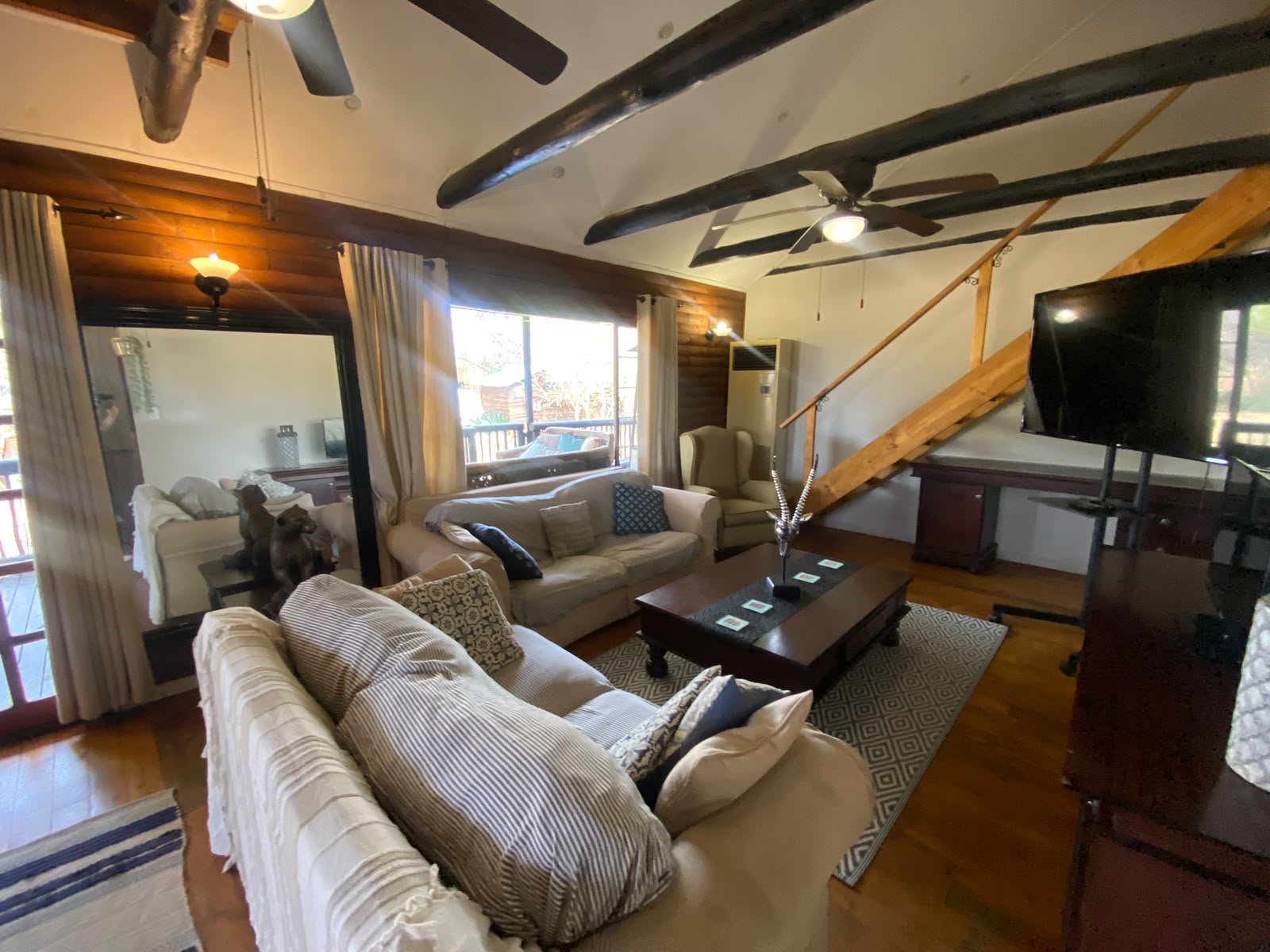 Spacious rustic lounge with exposed beams and multiple sofas at Blesbok Lodge