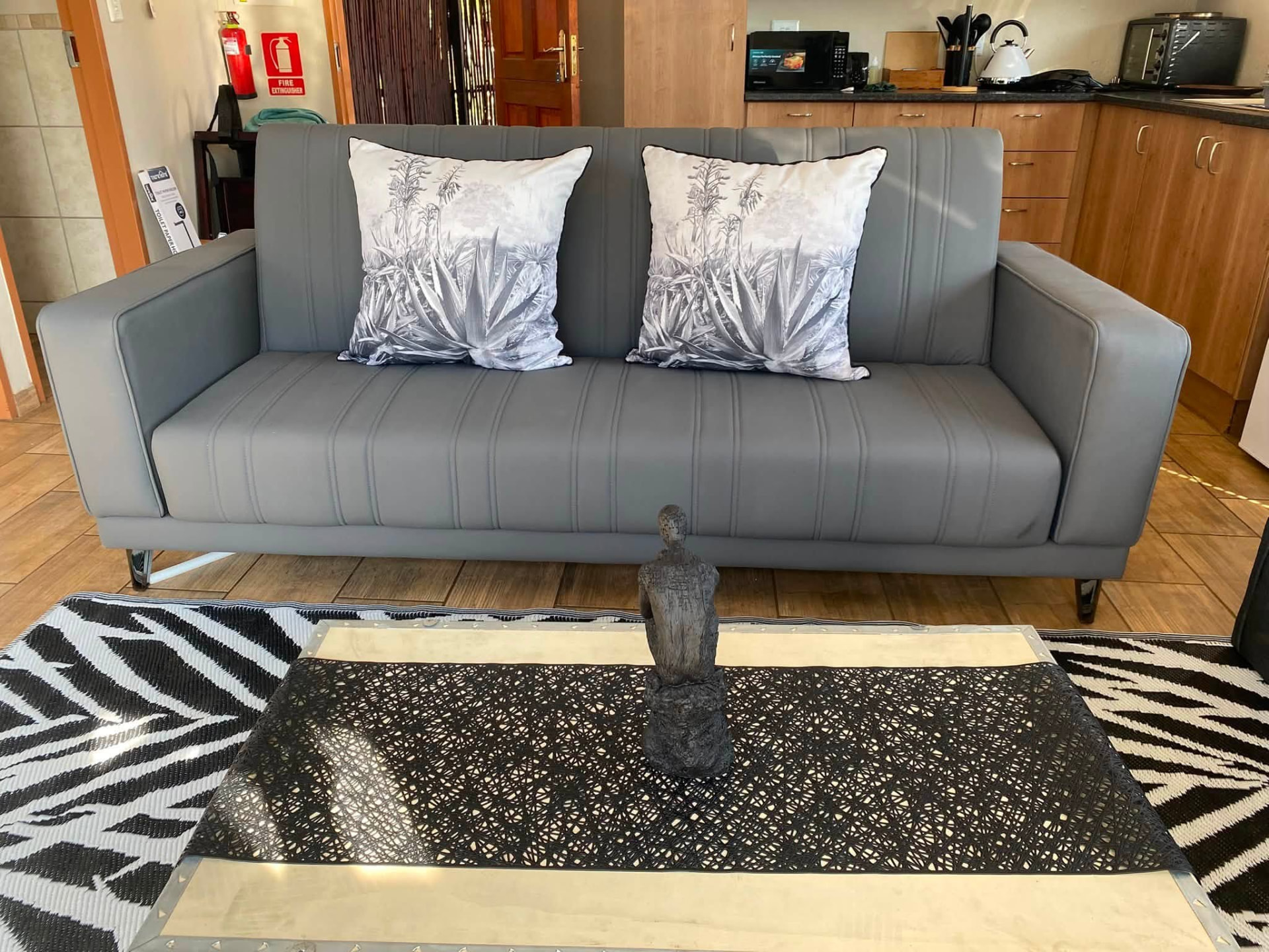 Lounge sofa with botanical cushions and kitchenette behind in the Aloe Suite