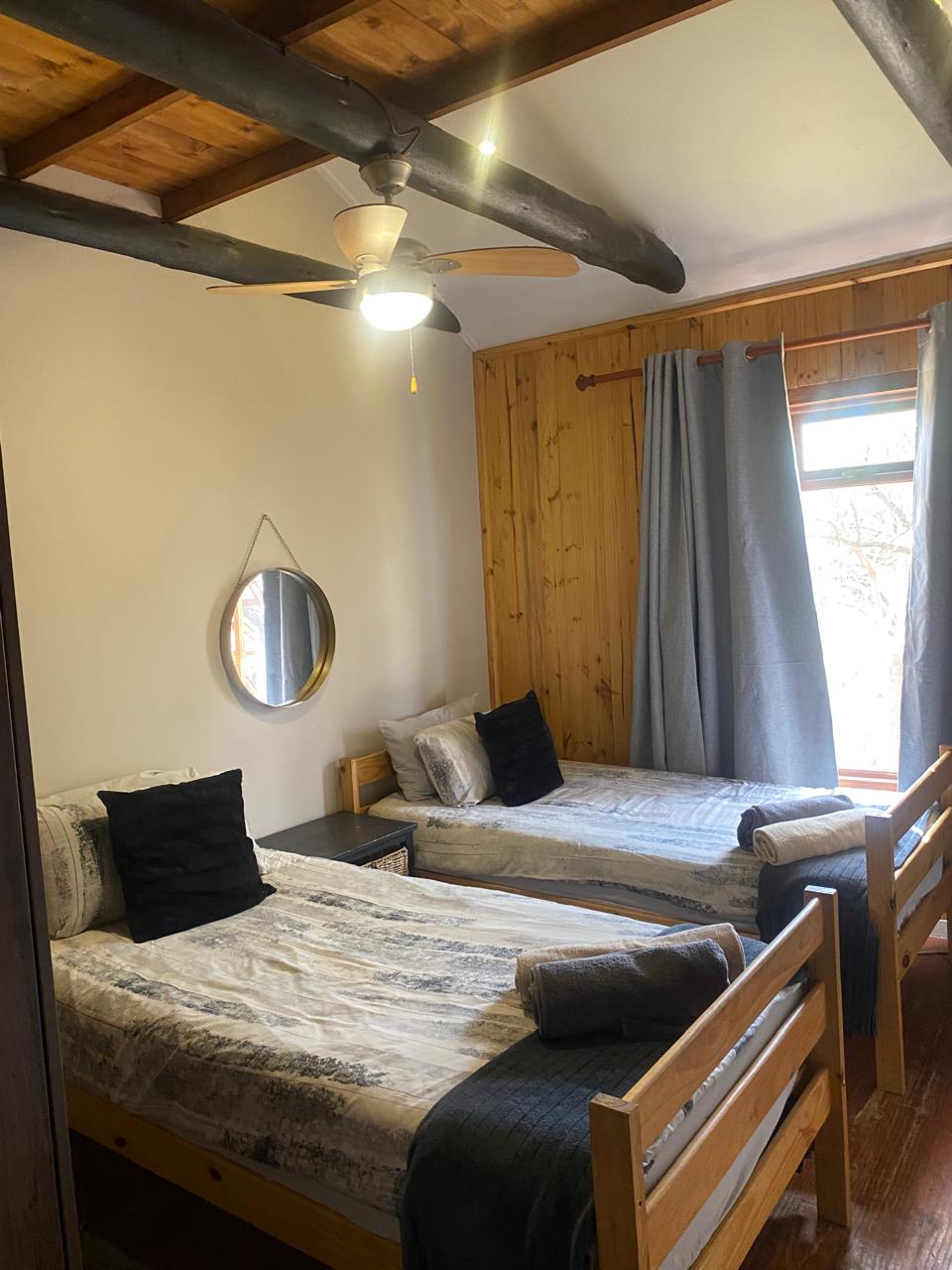 Twin bed bedroom with wood panelling and exposed beams at Blesbok Lodge