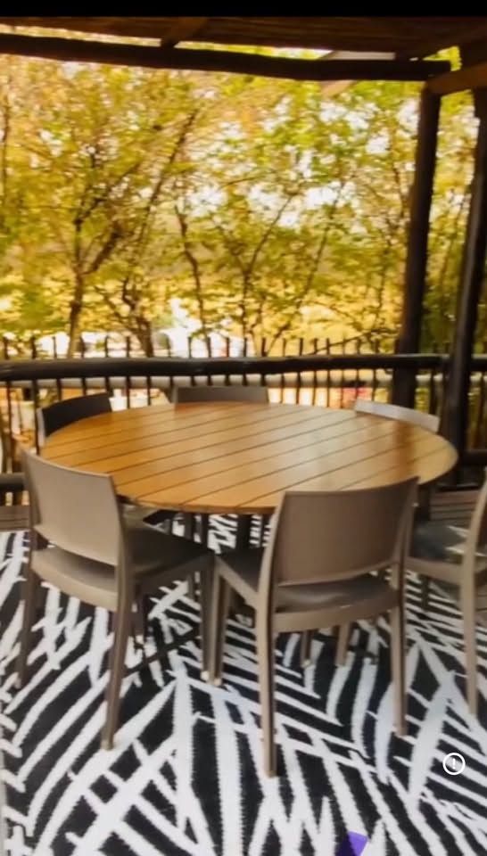 Stoep dining table set beneath the trees at Acacia Lodge