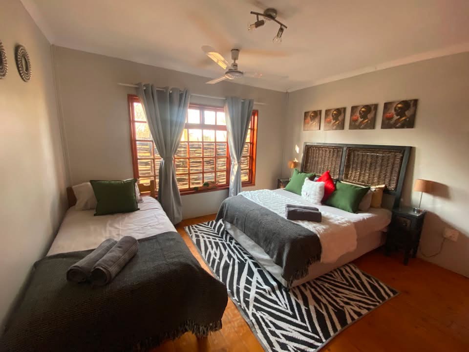 Second bedroom with a double and single bed and patterned rug at Acacia Lodge