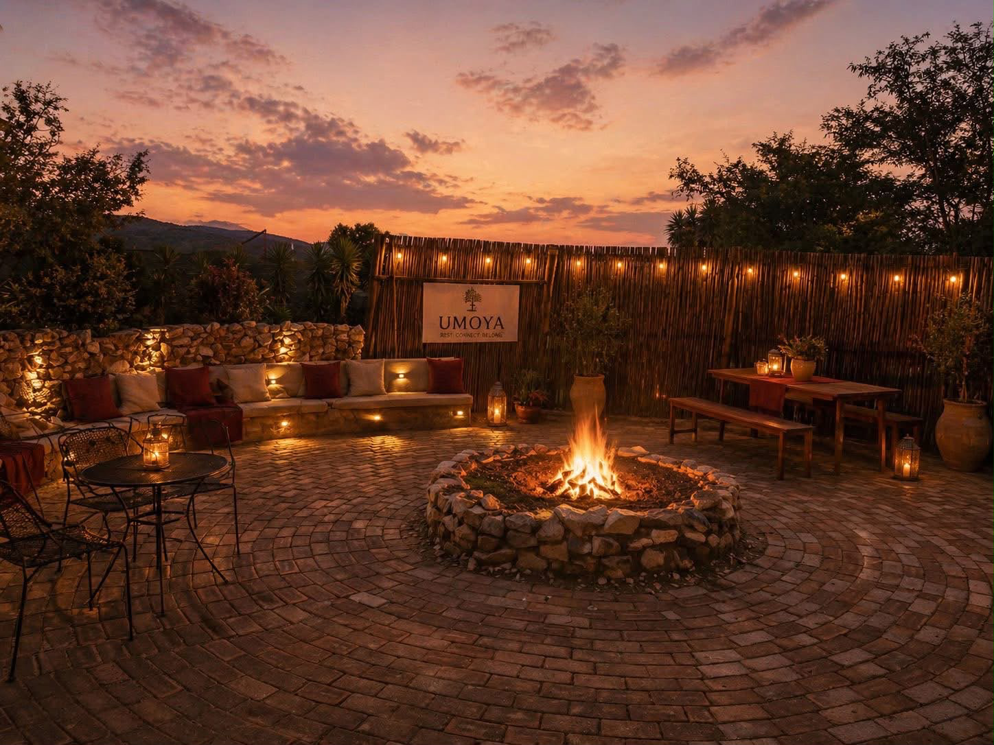 The Woodland Lodge boma firepit at sunset with the Umoya sign and lantern light